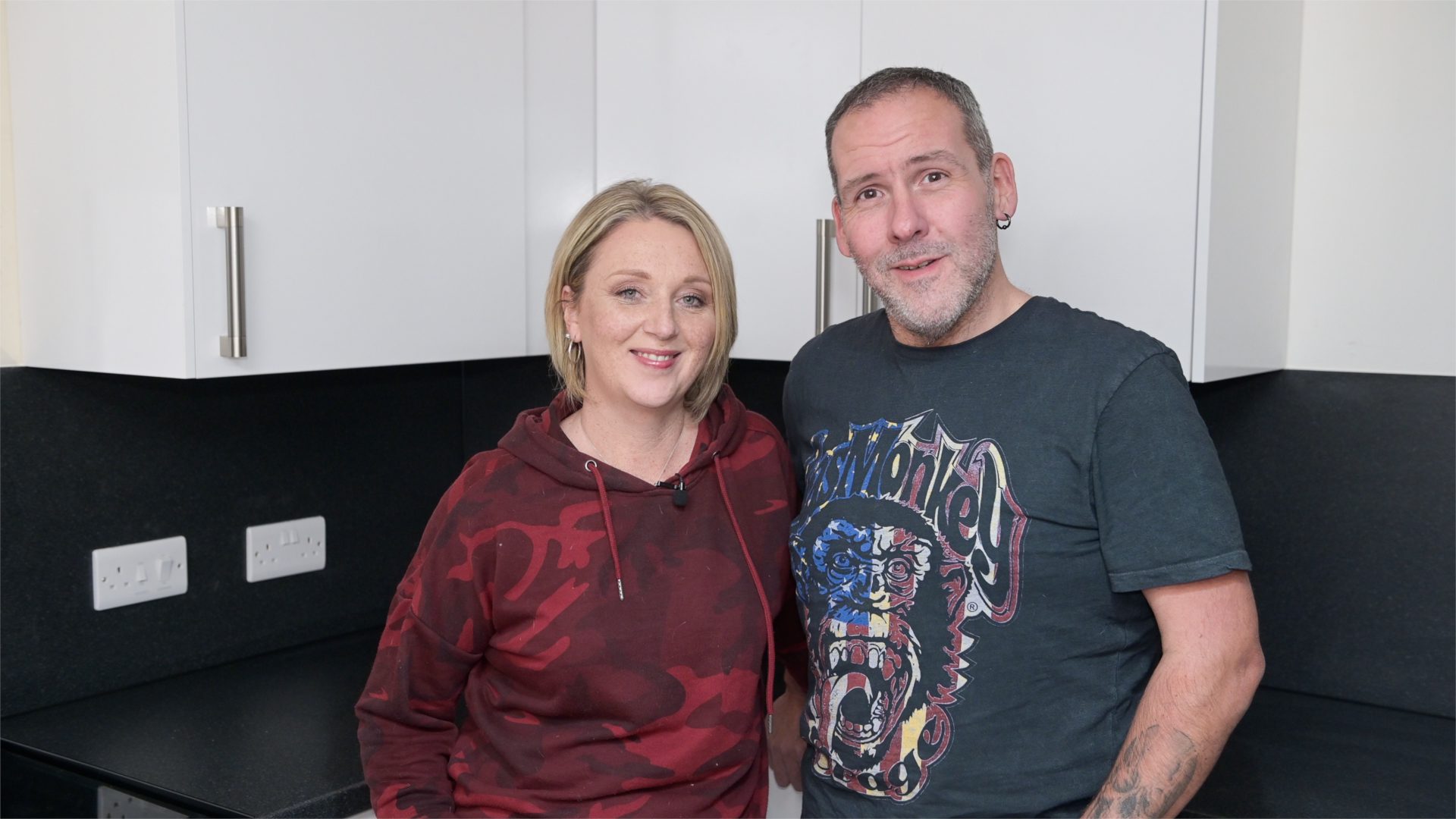 Man and woman standing in front of kitchen cabinets