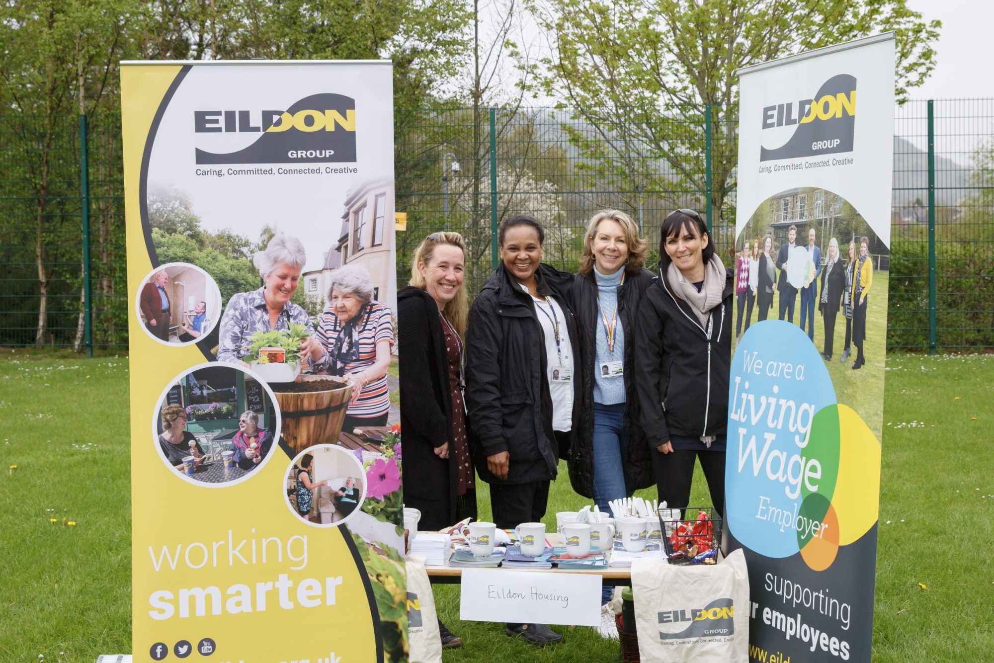 Three people standing behind a Eildon Group branded banner and table