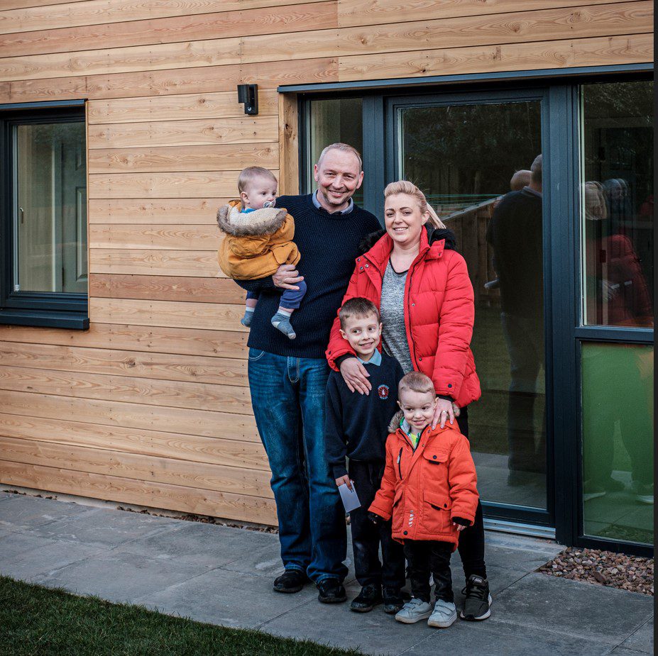 Two adults and three children standing together outside home